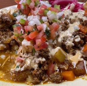 A plate of nachos with meat and vegetables on it.