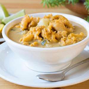 A bowl of soup with a spoon on a wooden table.