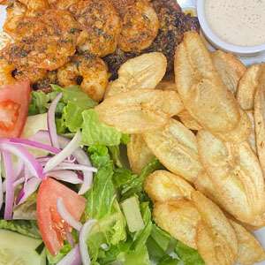 A plate with shrimp, chips and salad.