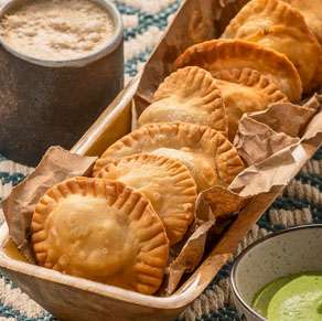 A bowl of empanadas and a bowl of guacamole.