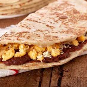 A stack of quesadillas with eggs on top.
