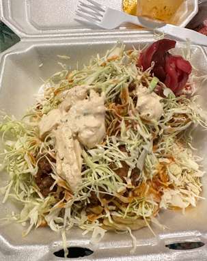 A tray of tacos with slaw and a fork.