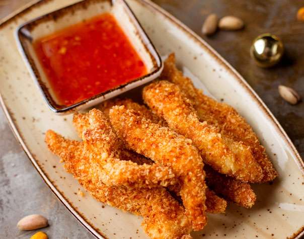 Fried chicken sticks with dipping sauce on a plate.