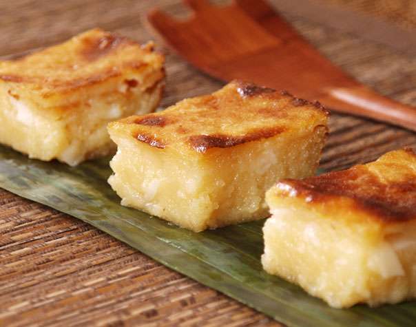 Three squares of dessert are sitting on a banana leaf.