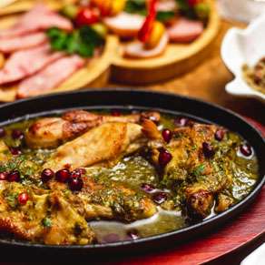Chicken with pomegranate sauce on a wooden table.