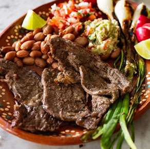 A plate with steak, beans and guacamole.