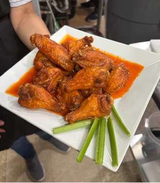 A person is holding a plate of chicken wings.
