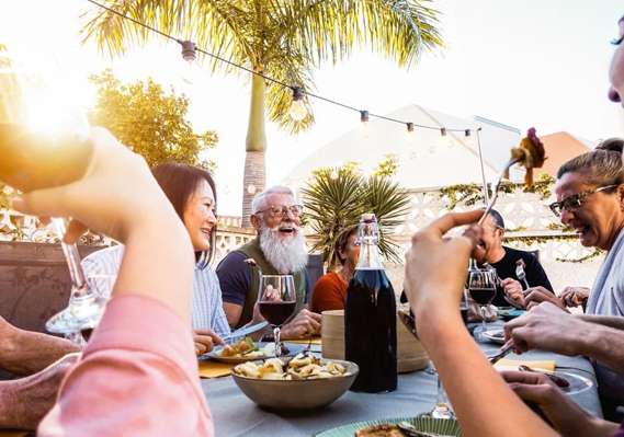A group of people sitting around a table and drinking wine.